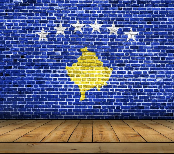 Bandeira do Kosovo pintada na parede de tijolo com piso de madeira — Fotografia de Stock