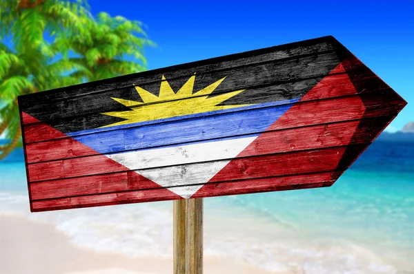 Cartel de madera con bandera de Antigua Barbuda sobre fondo de playa — Foto de Stock
