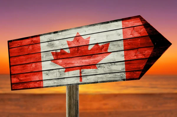 Kanada flagga på träbord logga på stranden bakgrund — Stockfoto