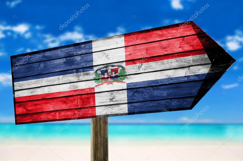 Dominican Republic Flag on wooden table sign on beach background