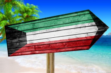 Kuwait Flag wooden sign on beach background clipart