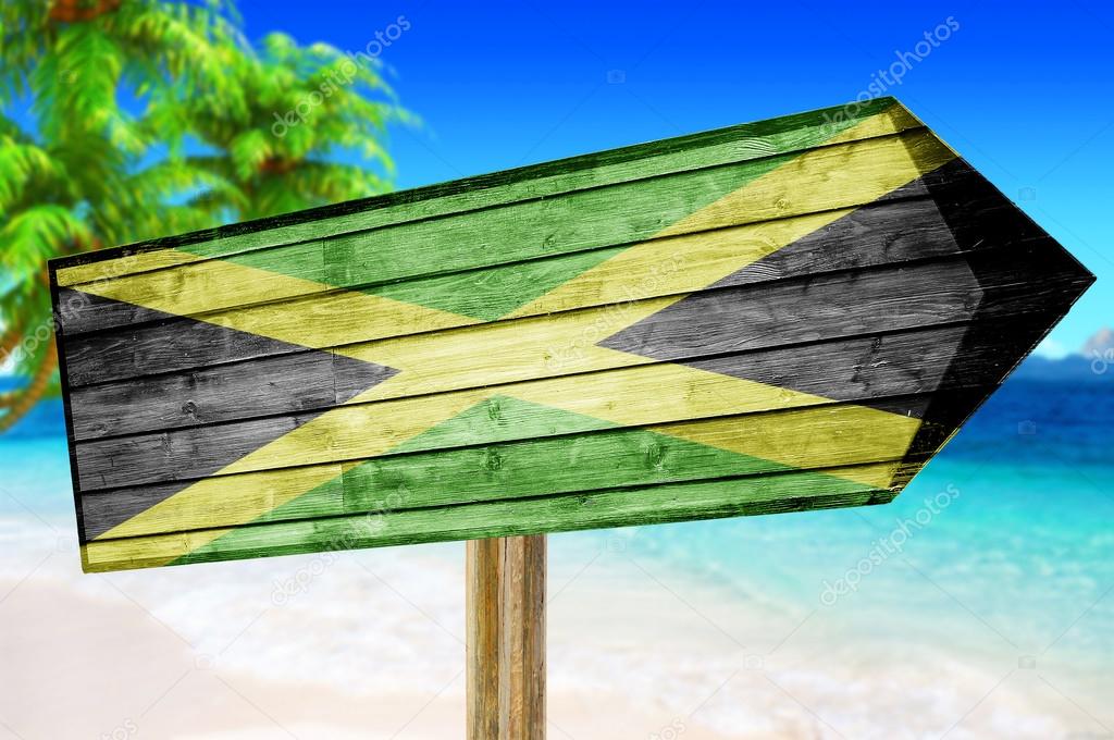 Jamaica flag wooden sign with on a beach background