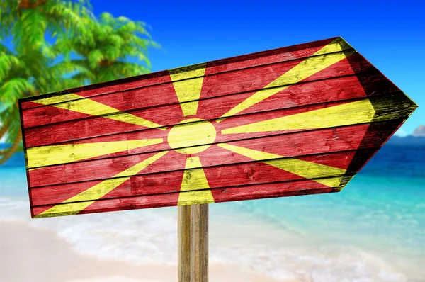 Cartel de madera con bandera de Macedonia sobre fondo de playa — Foto de Stock