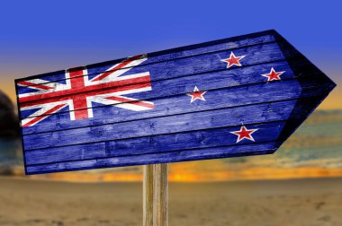 New Zealand Flag wooden sign on beach background clipart