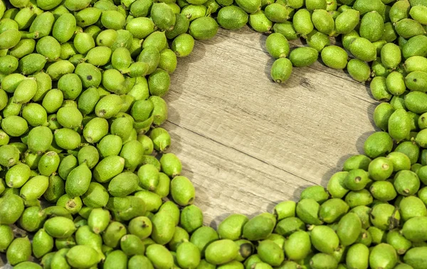 Veel jonge groene walnoten in bolsters op tafel in de vorm van horen — Stockfoto