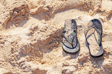 Bir kum okyanus plaj üzerinde siyah flip flop