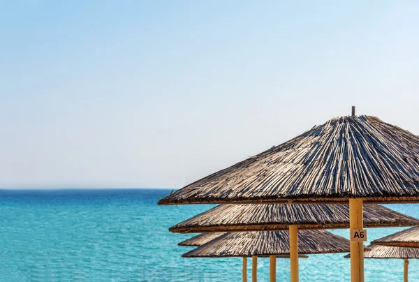 Halm paraply på vackra stranden bakgrund — Stockfoto