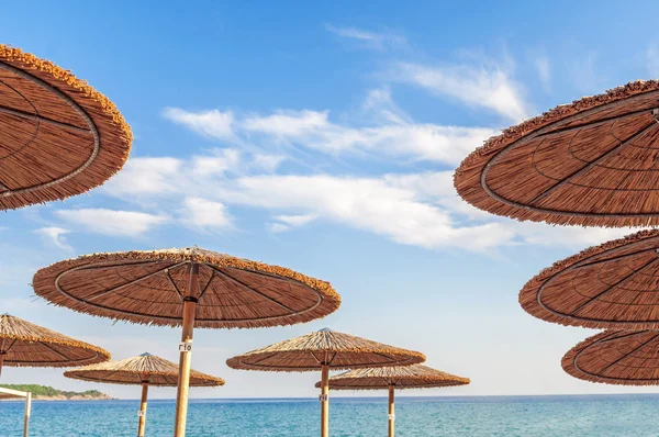 Halm parasoll och en vacker strand inbjudande att koppla av — Stockfoto