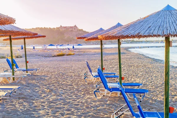 Vários sunbed azul, guarda-chuva palha no fundo da praia bonita — Fotografia de Stock