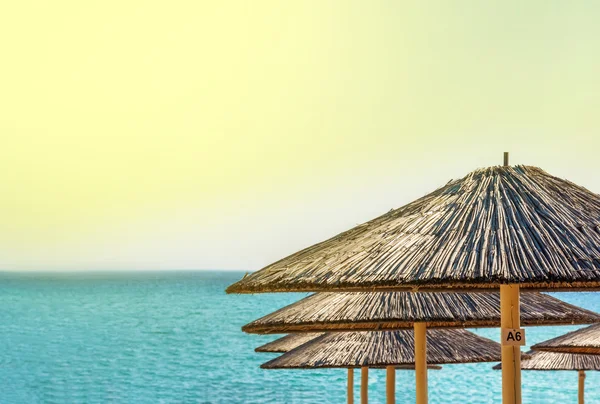 Sombrilla de paja sobre hermoso fondo de playa — Foto de Stock