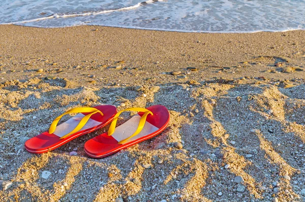 Chinelos em uma praia de areia oceânica — Fotografia de Stock