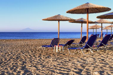 Şezlong, güzel yükselen güneş plaj arka plan üzerinde saman şemsiye