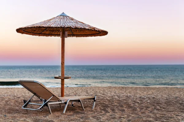 Solarium, halm paraply på vackra solnedgång stranden bakgrund — Stockfoto