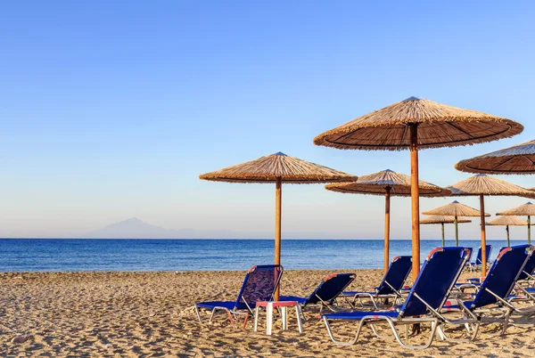 Ξαπλώστρα, άχυρο ομπρέλα σε όμορφο άνοδο ήλιο παραλία φόντο — Φωτογραφία Αρχείου