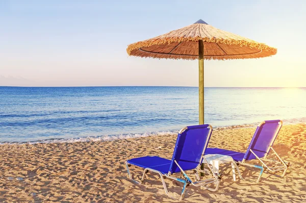 Due lettini blu, ombrellone di paglia su bellissimo sfondo spiaggia — Foto Stock