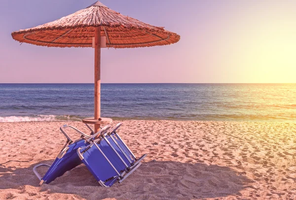 Tumbona, sombrilla de paja sobre hermoso fondo de playa — Foto de Stock