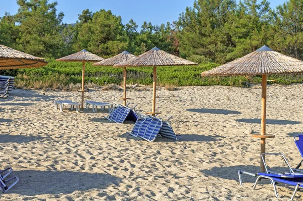 Cama de sol, guarda-chuva de palha em fundo de praia bonita na Grécia — Fotografia de Stock