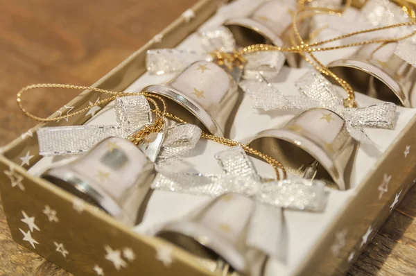 Six small christmas bells in box on table