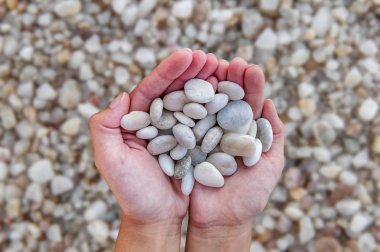 Eller kadın plaj arka plan üzerinde elinde tutan küçük taşlarla