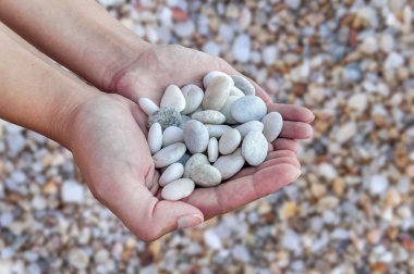 Eller kadın plaj taş zemin üzerine elinde tutan küçük taşlarla