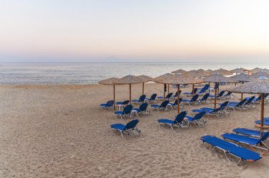 Bir sürü güzel yükselen güneş plaj arka plan üzerinde şemsiye şezlong, saman