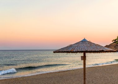 Reed şemsiye ve şezlong plaj mor günbatımı sahilde