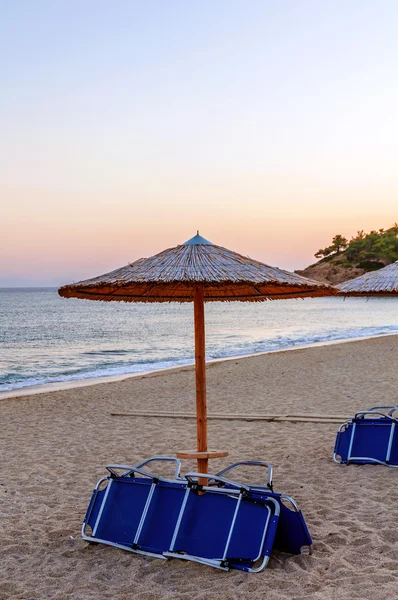 Guarda-chuvas Reed e praia sunbed na praia roxa do por do sol — Fotografia de Stock