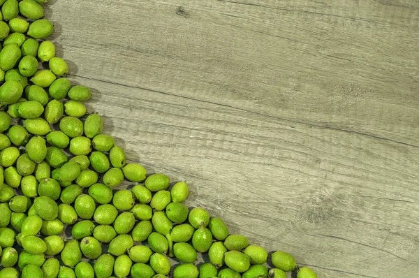 Groene jonge walnoten in bolsters op houten tafel — Stockfoto