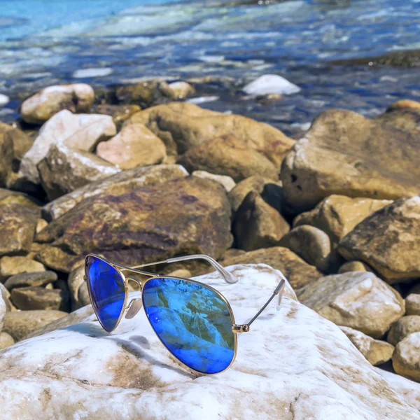 Солнечные очки синий летчик на пляже скалы — стоковое фото