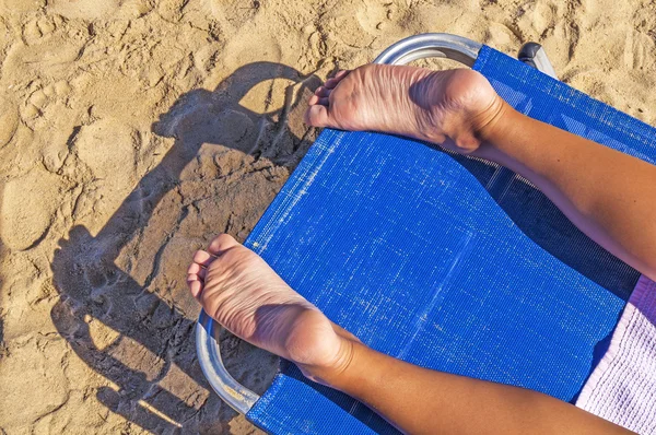 Mulher pés closeup de menina relaxante na praia na espreguiçadeira desfrutando do sol no dia ensolarado de verão — Fotografia de Stock