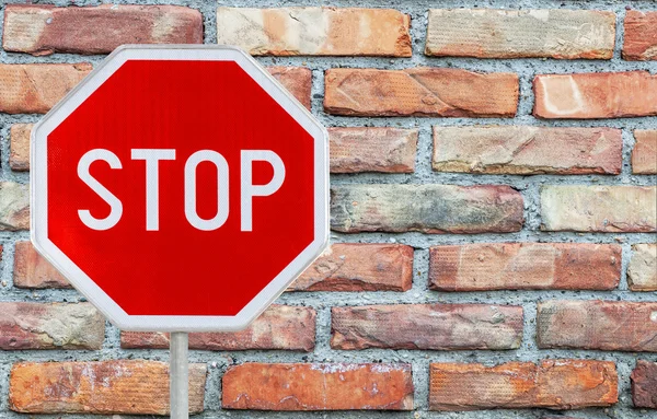 Red stop sign on a rod with Background of red brick wall — Stock Photo, Image