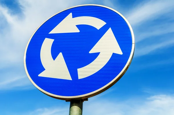 Roundabout crossroad road traffic sign against blue sky — Stock Photo, Image