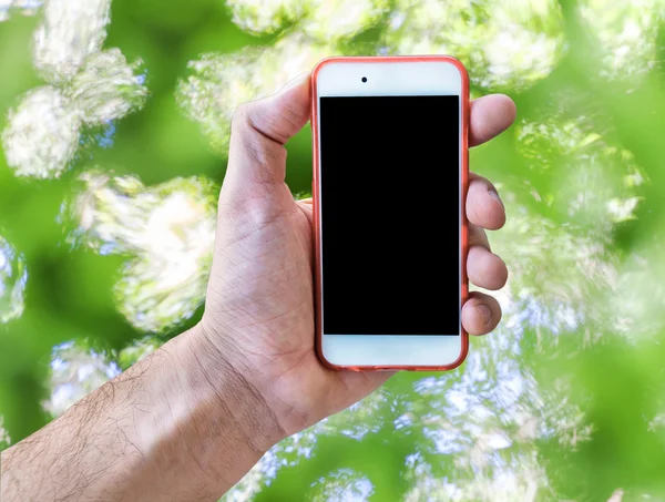 Mano que sostiene la pantalla táctil del teléfono móvil aislado fondo borroso verde — Foto de Stock