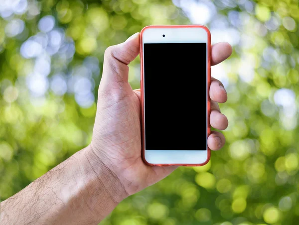 Mano que sostiene la pantalla táctil del teléfono móvil aislado fondo borroso verde — Foto de Stock