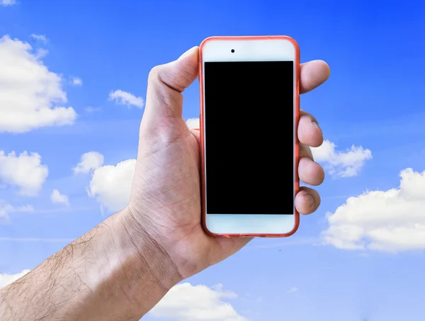 Mano que sostiene el teléfono móvil de la pantalla táctil aislado en cielo azul nublado — Foto de Stock