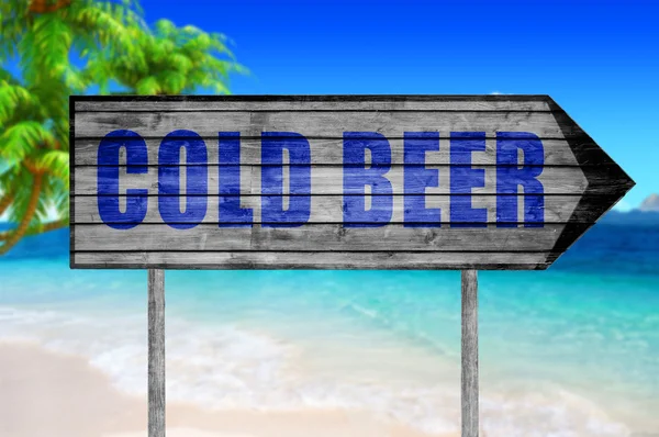 Soğuk bira ahşap işareti ile bir plaj arka planda — Stok fotoğraf