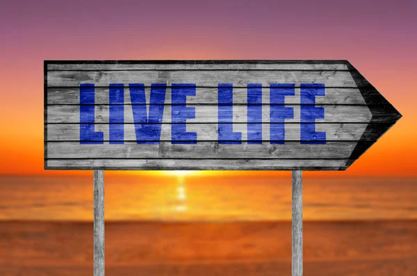 Signo de madera Vida viva con una playa en el fondo — Foto de Stock