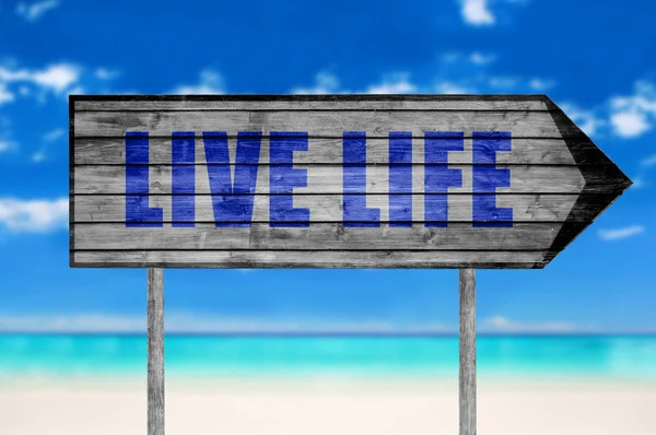 Signo de madera Vida viva con una playa en el fondo — Foto de Stock