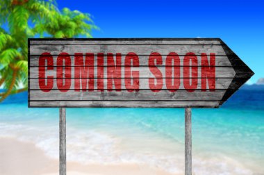 Plaj arka plan üzerinde kırmızı Coming Soon ahşap işareti ile