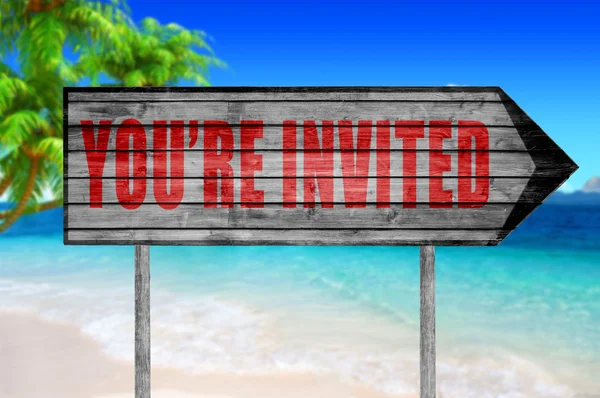 Rot sind Sie eingeladen! Holzschild mit einem Strand im Hintergrund — Stockfoto
