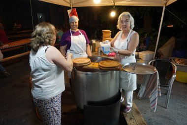 Kadınlar Galiçya 'daki hac yolculuğunda yemek için dev bir tencerede ahtapot pişiriyor.