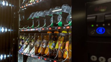 Çeşitli renklerde meşrubat şişeleri, onları soğuk ve tüketilmeye hazır tutan bir dağıtım makinesine yerleştirilmiş.