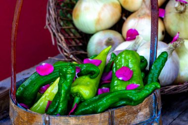 Beyaz soğanlı sepetin önünde taze toplanmış yeşil biber.