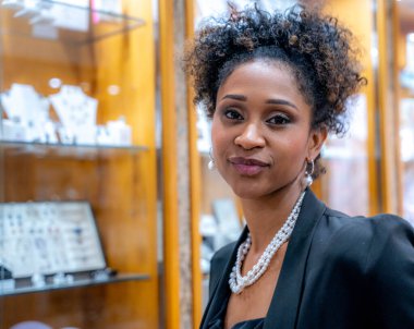 Kıvırcık saçlı ve inci kolyeli zarif bir genç kadının göğüs hizasında, tatmin olmuş bir ifadeyle doğrudan kameraya bakıyor..