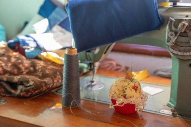 Siyah iplik makaralı ve iğneli yeşil bir dikiş makinesinin ayrıntıları. Geleneksel dikiş, tekstil tasarımı ve yaratıcı el sanatlarını temsil ediyor..