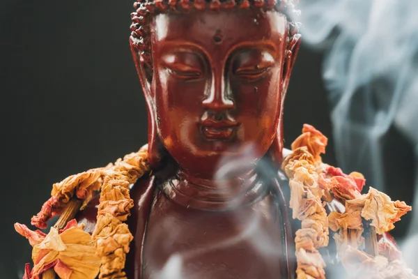 Статуя Будды в приношениях цветов. Похоронная статуя Будды Шакьямуни, украшенная венками из цветов — стоковое фото