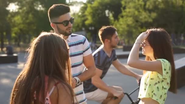 Молодой красивый бородатый парень флиртует с двумя модными девушками на улице — стоковое видео