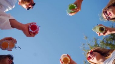 Arkadaşların havuz partisinde eğlenmesi, otel havuzunun yanında renkli yaz kokteylleri içmesi. İnsanlar yaz köşkünde yavaş çekimde taze meyve suyu içerek kadeh kaldırıyorlar..