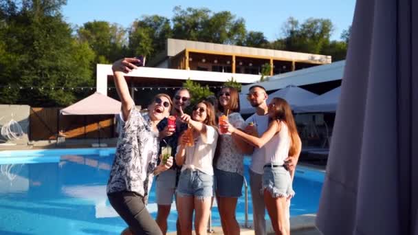 Glimlachende vrienden die selfie maken met smartphone op een feestje aan het zwembad met frisse kleurrijke cocktails bij het zwembad op zonnige zomerdag. Vrouw maakt foto in luxe villa op tropische vakantie. — Stockvideo