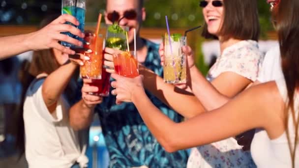 Vista cercana de los amigos divirtiéndose en la fiesta de la piscina de verano, tintinear vasos con cócteles y bailar cerca de la piscina del hotel al aire libre. La gente brinda bebiendo jugo en villa de lujo en cámara lenta. — Vídeo de stock